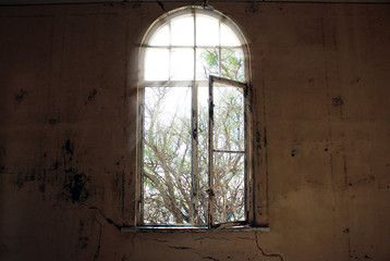 window without glass and dirty walls in an abandoned house
