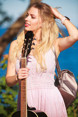 Blonde woman with acoustic guitar on seaside