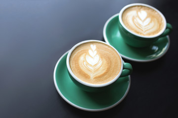 Two cups of cappuccino or latte coffee with milk on bark table. Beautiful foam. Greenery ceramic cups, place for text.