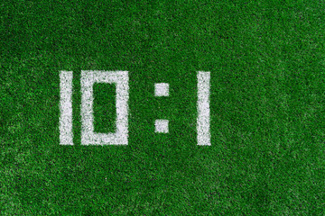 Football score.White numbers ten and one are drawn on the green grass,creative scoreboard