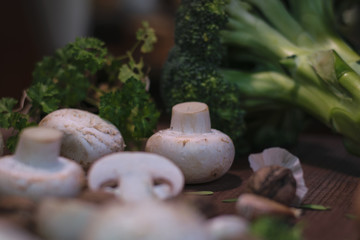 Fresh vegetables and nuts are on the table. Nuts, near champignons and onions with garlic, green broccoli with a sprig of seasoning