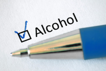Questionnaire –  blue pen and the inscription ALCOHOL with check mark on the white paper