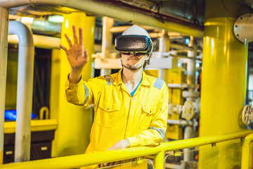 Young woman in a yellow work uniform, glasses and helmet uses virtual reality glasses in industrial...
