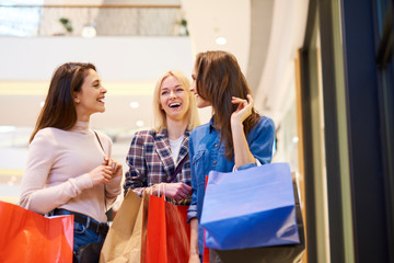 Naklejka na ściany i meble Three girls enjoying the shopping in the shopping mall
