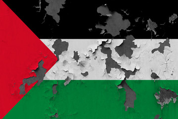 Close up grungy, damaged and weathered Palestine flag on wall peeling off paint to see inside surface.