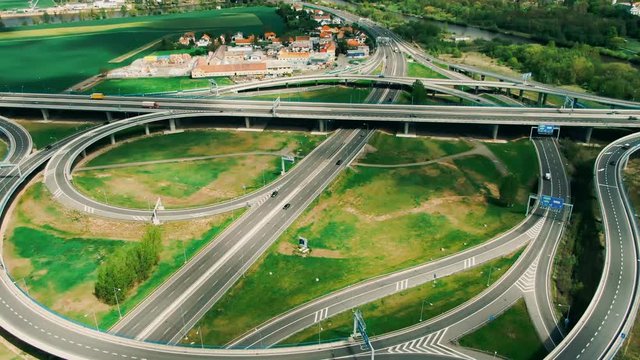 Aerial top down view on multilevel interchange overpass in Zbraslav showing afternoon traffic under sun and cloud