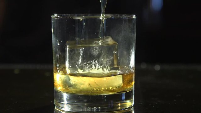 Whiskey being poured in a glass over ice