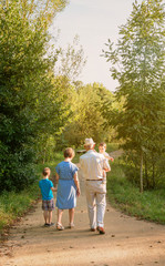 Back view of grandparents and grandchildren walking on a nature path