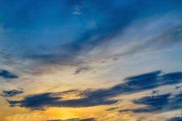 Blue sky with gold clouds - dramatic sunset, beautiful natural background. Setting sun illuminates the clouds.