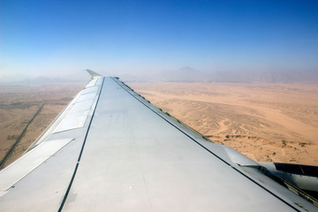 Fototapeta na wymiar view from the window of the plane to the desert and the wing of the plane