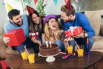 Young group of happy friends celebrating birthday at home and having fun.