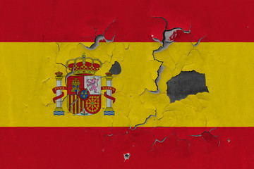 Close up grungy, damaged and weathered Spain flag on wall peeling off paint to see inside surface.