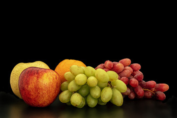 Orange, grapes, apple and pyrus pyriflora on a black background.