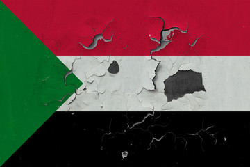 Close up grungy, damaged and weathered Sudan flag on wall peeling off paint to see inside surface.