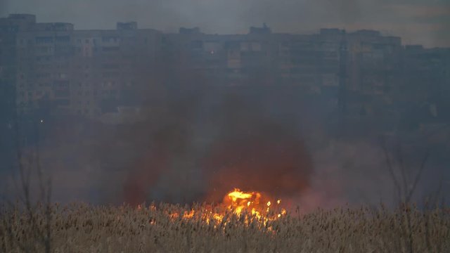 High buildings on the Dnipro bank and glowing flame across the river at night    