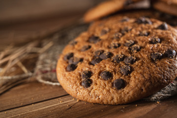 Fototapeta na wymiar Fresh chocolate americana cookies on wooden table. Chocolate chip cookies on rural background.