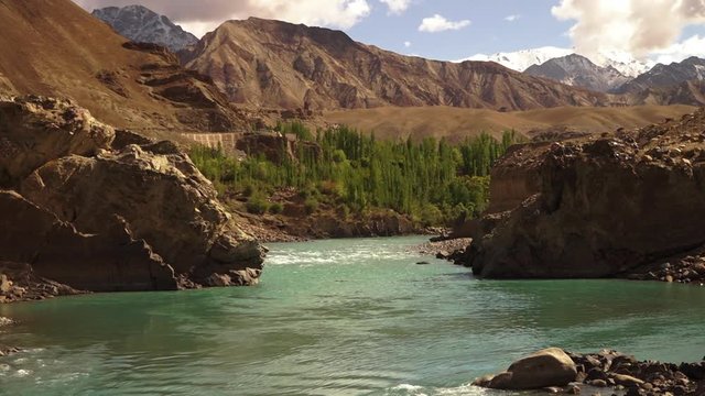 Captivating wide still shot of bubbling Gangotri glacier spring water, flowing through an eroded valley.  Perfect view of white snow  covered Himalayas ranges and adjacent mountains, Uttarkashi