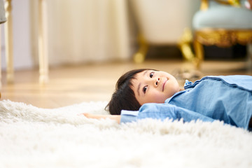 little asian boy lying on back on carpet
