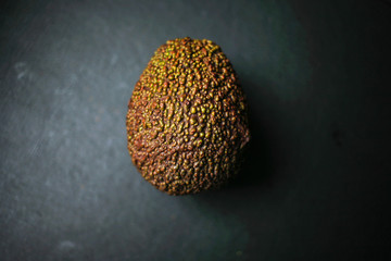 Whole avocado on black background top view
