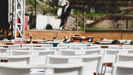 Waiting for an outdoor concert. Empty white simple chairs with backrest in the summer theater to watch a concert on stage.