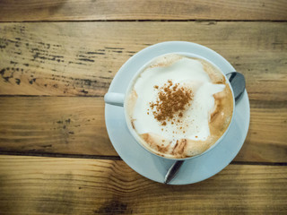 Cup of cappuccino coffee on a wooden background