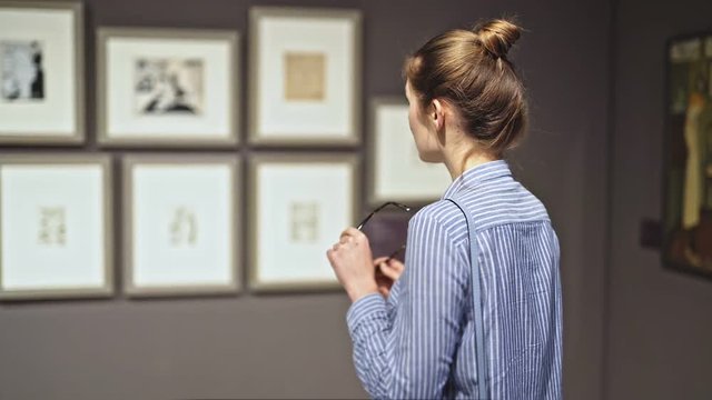 woman visitor in historical museum looking at pictures at museum of arts