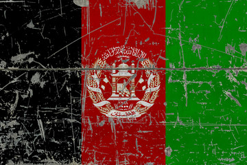 Grunge Afghanistan flag on old scratched wooden surface. National vintage background.