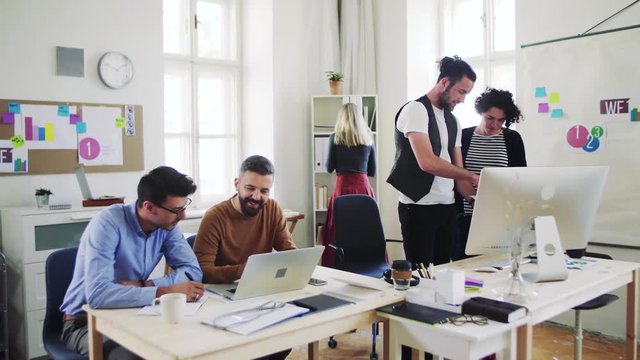 Group of young businesspeople with laptop working together in a modern office.