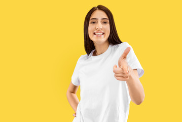 Happy girl showing sign of OK. Beautiful female half-length portrait isolated on yellow studio background. Young smiling woman. Negative space. Facial expression, human emotions concept.