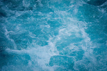 Ocean wave water sea of rippled water with white wave bubbles near the big boat on summer holiday.