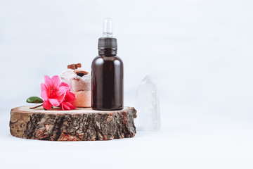 bottle of eco-friendly oil for skin care on a white background with flowers and crystal