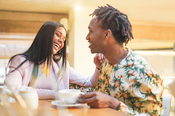 Happy black couple drinking coffee inside vintage bar restaurant - Trendy people having fun talking and laughing at breakfast time - Love and lifestyle concept - Focus on woman face