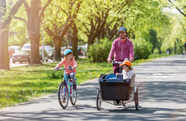 Father and daughters having a ride with cargo bike during spring