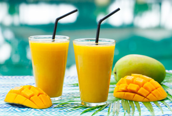 Fresh tropical fruit smoothie mango juice and fresh mango on a outdoor tropical background.