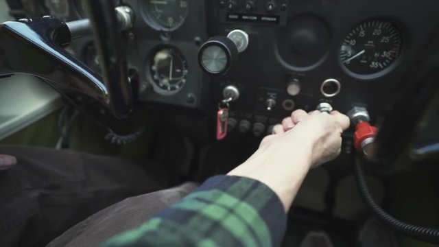 Pilot adjusts knobs inside the cockpit of a small plane
