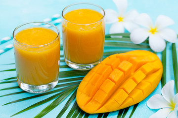 Fresh tropical fruit smoothie mango juice and fresh mango on blue background.