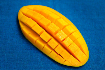 Fresh mango organic product on blue textile background. Close up.