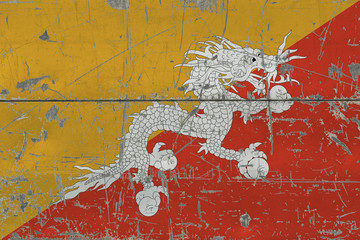 Grunge Bhutan flag on old scratched wooden surface. National vintage background.