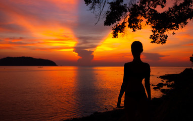 Naklejka na ściany i meble Woman looking at sunrise on the sea