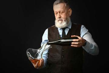 Portrait of elegant mature sommelier on dark background