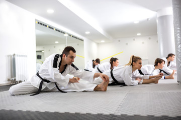 Experienced martial art fighters and one physically disabled young girl stretching together