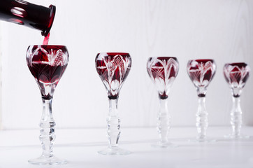 Closeup of pouring strong bitter liqueur into the old-fashioned glasses