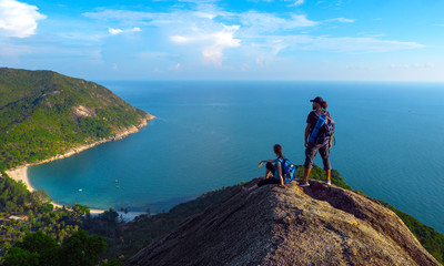 Man and woman stand on on top of cliff in summer mountains at morning time and enjoying view of nature