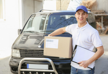 Delivery man with parcel and clipboard near car outdoors