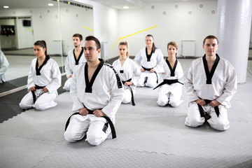 Fototapeta na wymiar Group of experienced martial artists and para-martial artist sitting together after taekwondo workout