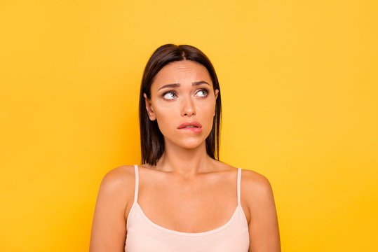 Close up photo beautiful she her lady look empty space fear hide eyes bite lip bad wrong unsuitable situation feel guilty wear casual pastel tank-top outfit clothes isolated yellow bright background