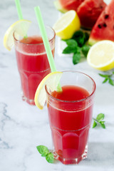 Cold watermelon lemonade with mint and lemon in glass glasses and ingredients for lemonade on a light background.