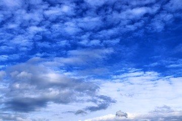 Interesting white and dark mixed cloud formations on a blue sky in spring