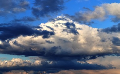 Interesting white and dark mixed cloud formations on a blue sky in spring
