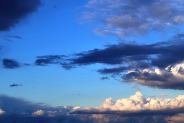 Interesting white and dark mixed cloud formations on a blue sky in spring